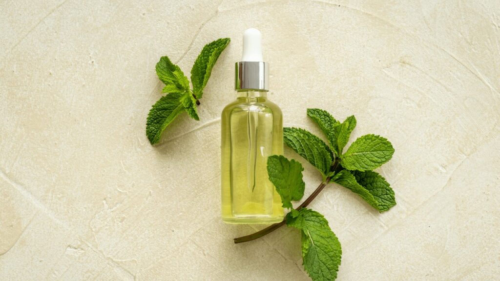 Olejek eteryczny położony wśród kawałków mięty