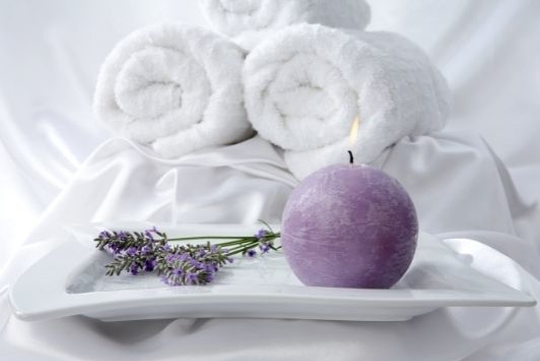 Gałązka lawendy leżąca obok świecy nawiązuje do przyjemnych odczuć podczas aromaterapii